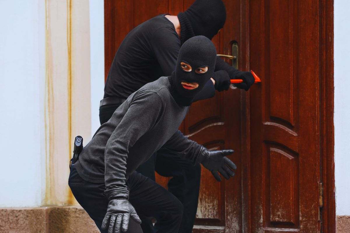 Ladri mascherati che forzano un portone