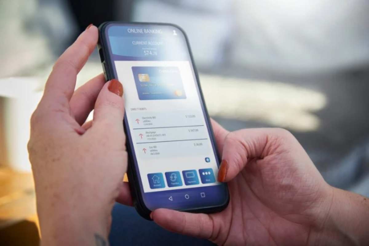 persona con telefono in mano guarda l'app della banca 