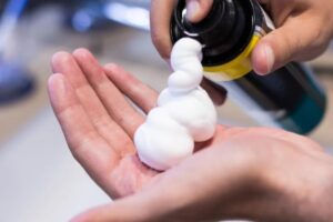 Persona spruzza sulla mano la schiuma da barba