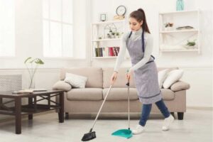 donna pulisce il pavimento con la classica scopa e paletta