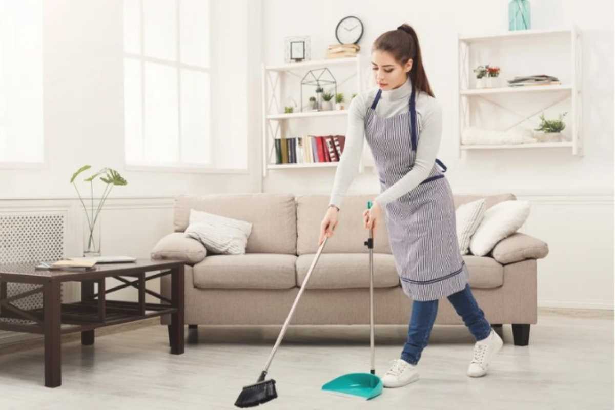 donna pulisce il pavimento con la classica scopa e paletta 