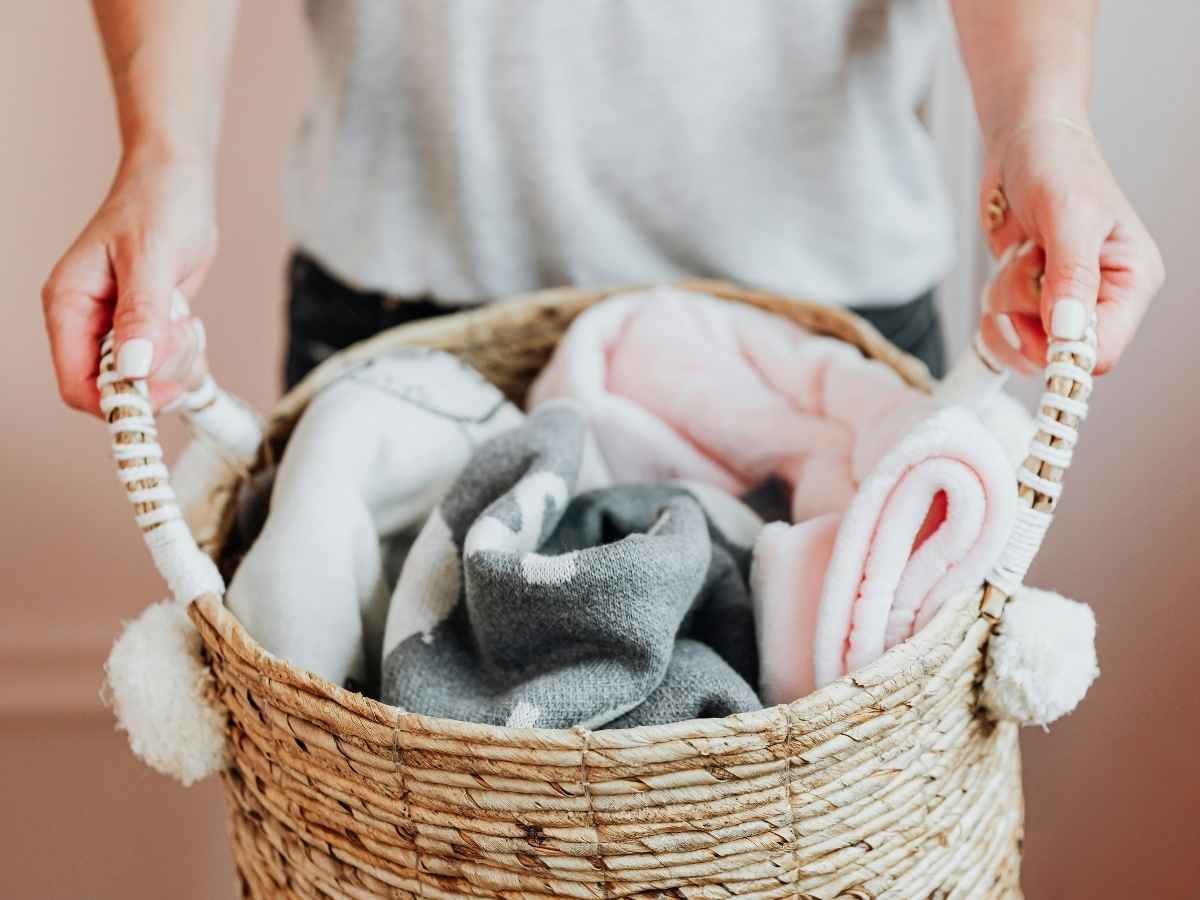 donna che tiene in mano una cesta del bucato contenente coperte di lana