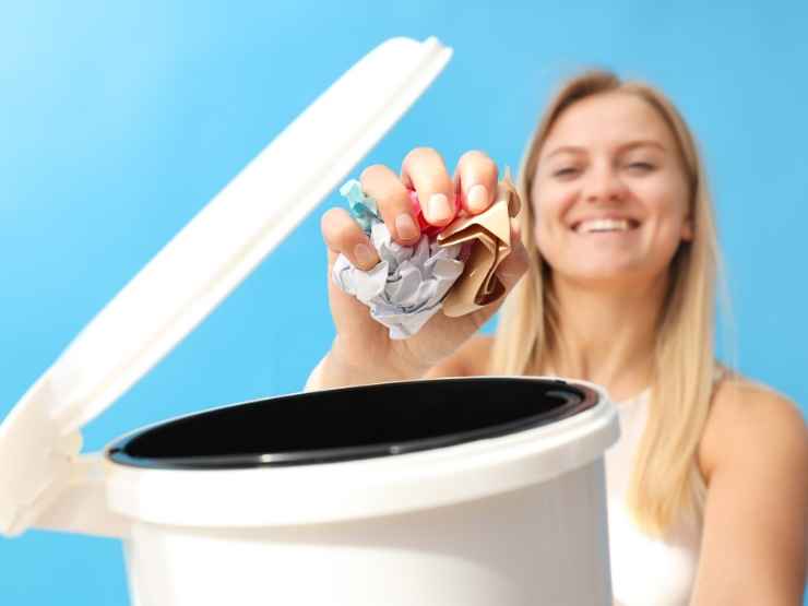 pattumiera aperta e donna che getta via carta con espressione sorridente