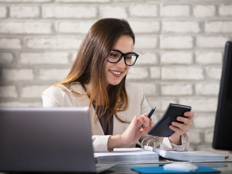 donna davanti al pc che consulta calcolatrice e sorride