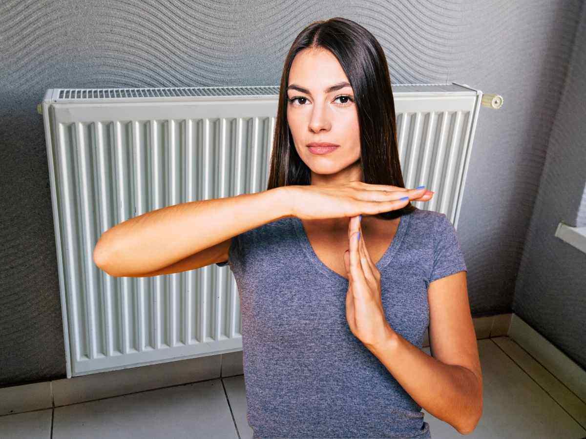 sullo sfondo termosifone donna in primo piano che mima stop