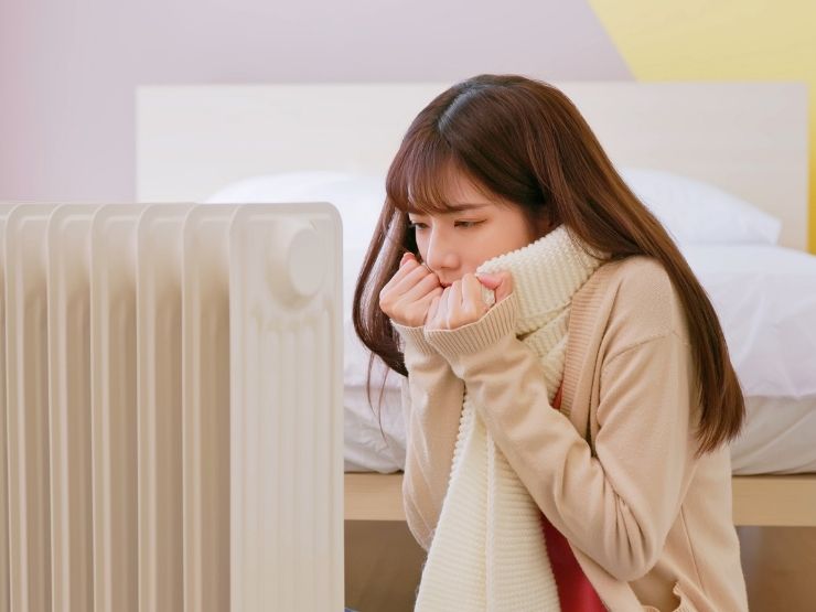 donna davanti al termosifone che sente freddo