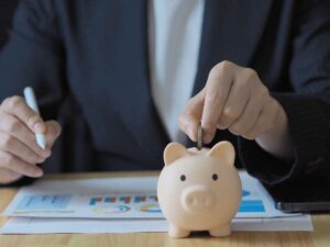 impiegato bancario che esamina documenti e mette moneta nel salvadanaio