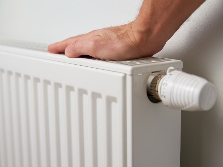 uomo che appoggia mano sul termosifone