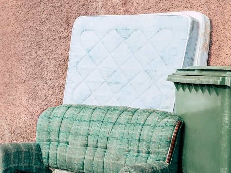 materasso e vecchio divano accanto ad una pattumiera