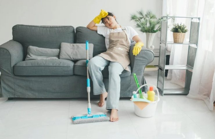Donna sul divano stanca per aver pulito il pavimento 