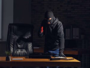 ladro che è entrato in casa e scruta con una torcia