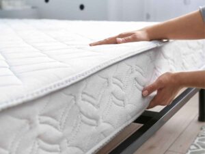 primo piano di una donna che solleva il materasso del letto