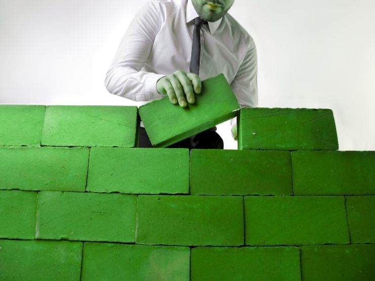 uomo che assembla mattoni verdi, idea di case green e bioedilizia