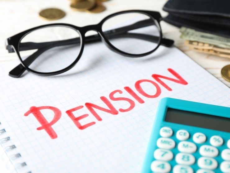 scrivania con fogli e calcolatrice, scritta pensioni