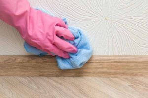 persona pulisce i battiscopa