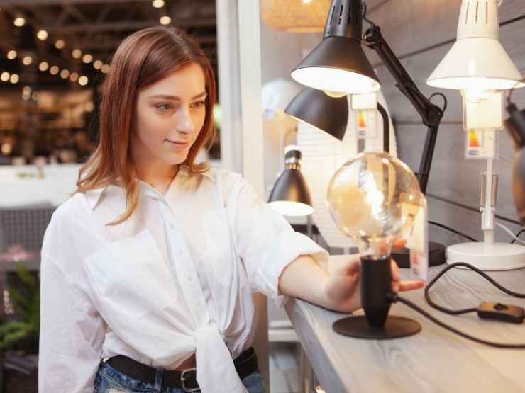 donna in negozio di illuminazione che ammira una lampada da tavolo