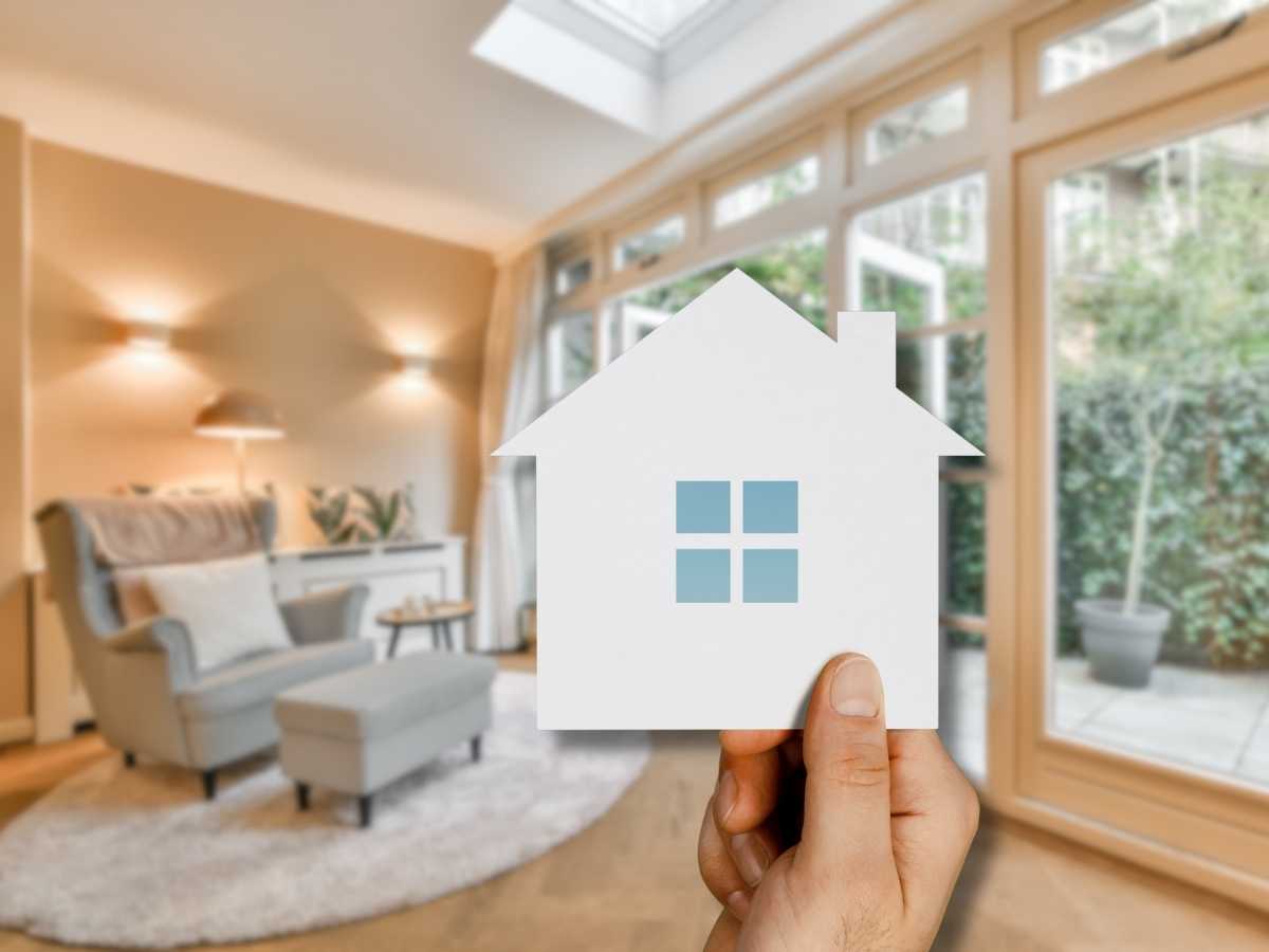sfondo casa in primo piano mano che mostra la sagoma di una casa