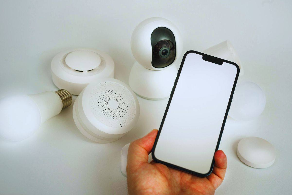 Uomo che tiene in mano uno smartphone davanti a oggetti smart