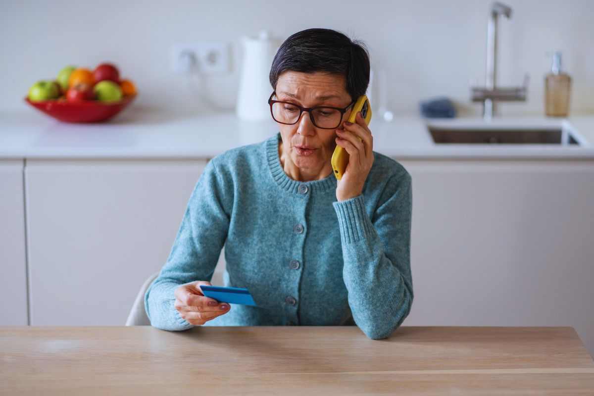 Donna anziana al telefono che detta numero carta