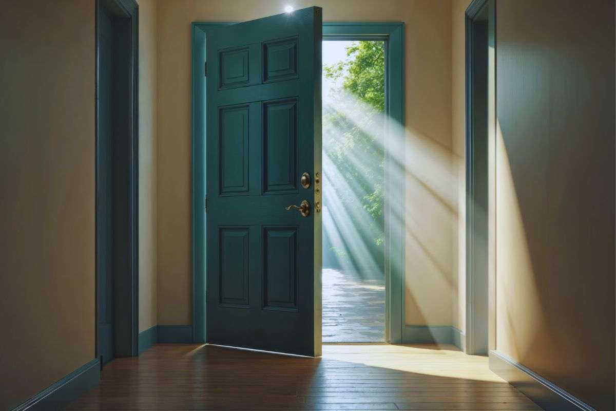 Porta aperta da cui filtrano raggi di luce