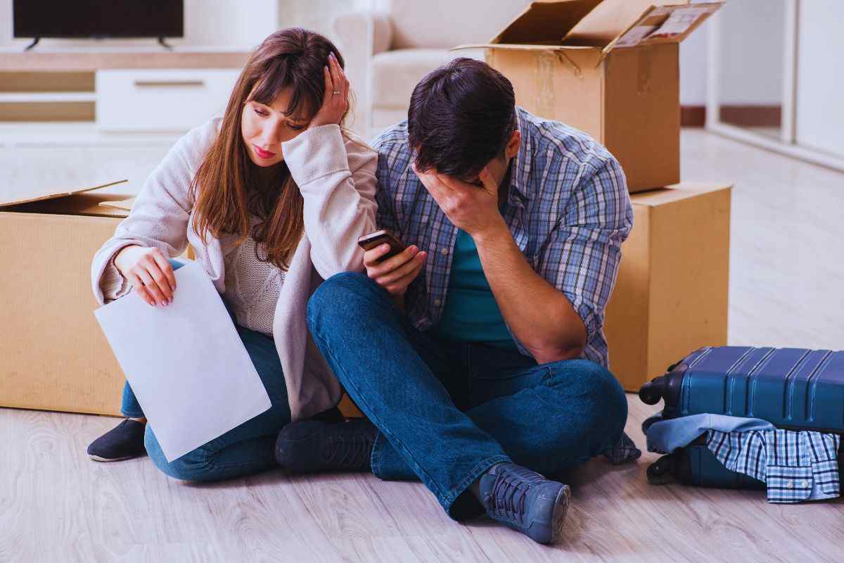 Coppia seduta sul pavimento davanti a scatoloni per il trasloco