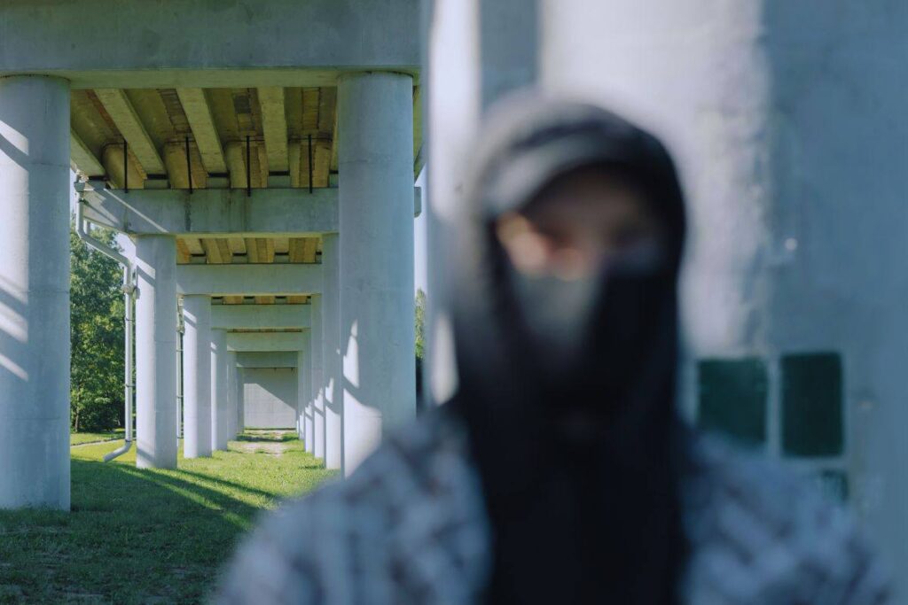 Uomo incappucciato che cammina sotto un ponte