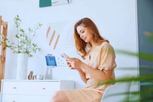 Ragazza sorridente che utilizza funzioni smart home grazie al telefono