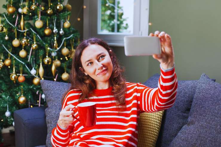 Donna che scatta un selfie davanti l'albero di Natale