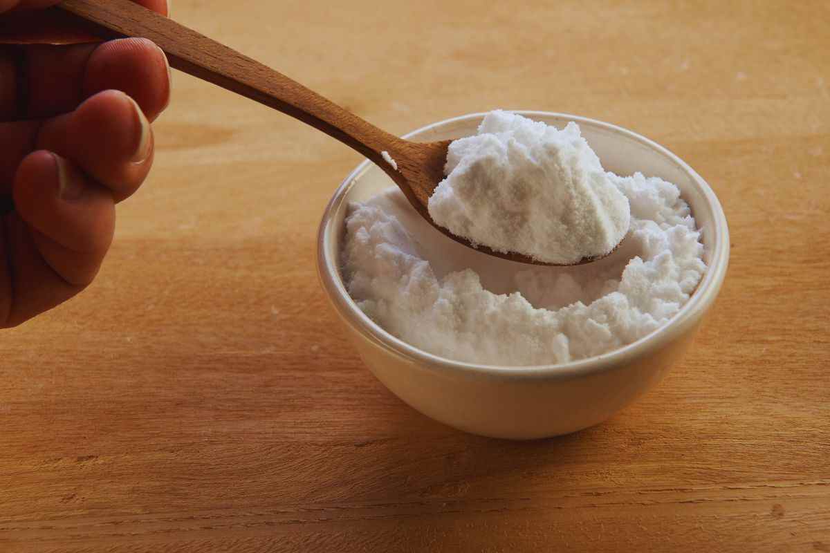 Persona che prende un cucchiaio di bicarbonato da una ciotola