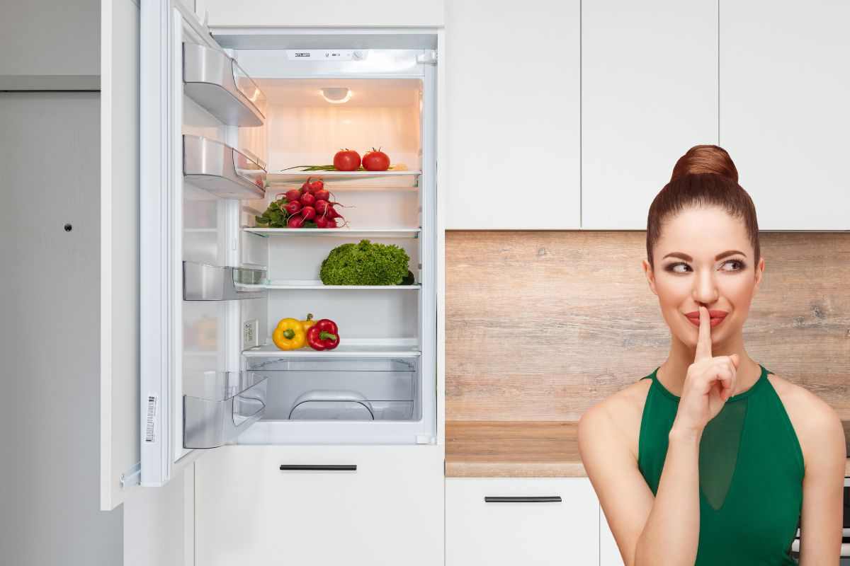 Donna che fa il gesto del silenzio accanto ad un frigo aperto