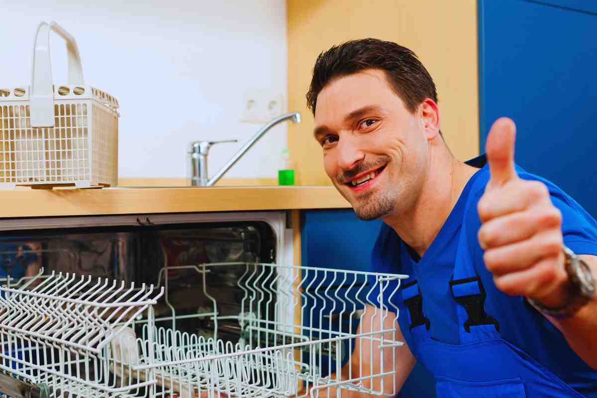 Uomo chinato su una lavastoviglie che mostra il pollice in segno di approvazione