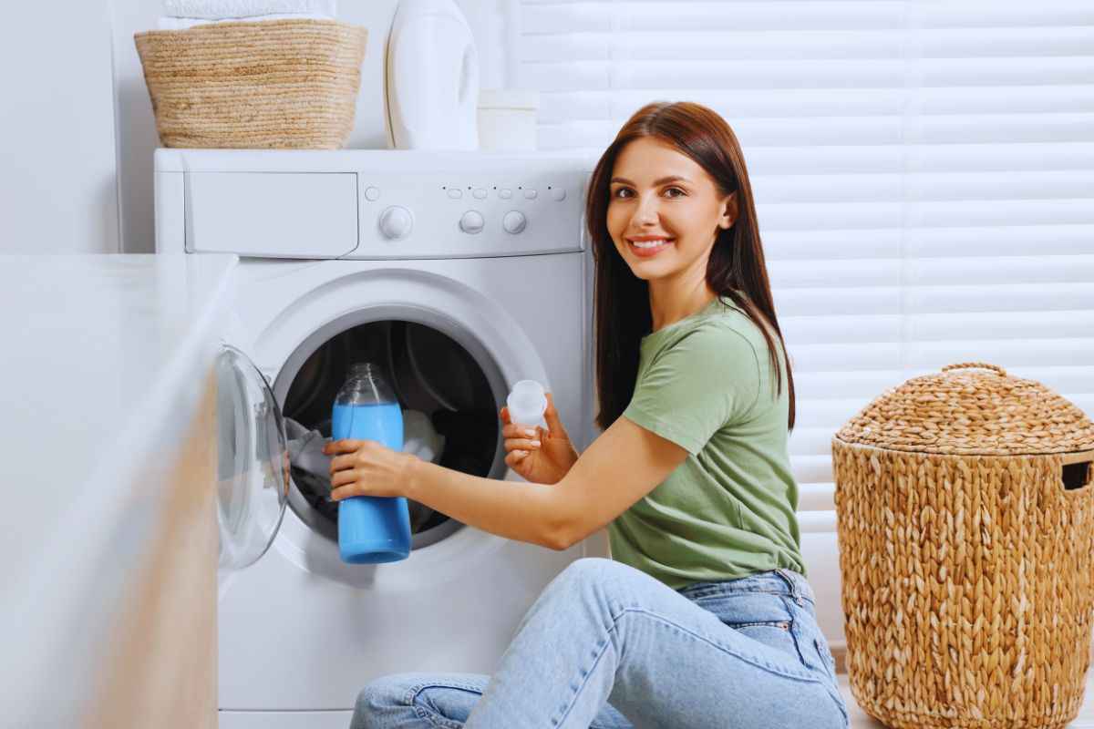 Donna che mette l'ammorbidente in lavatrice