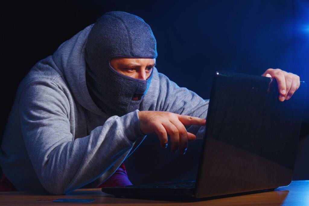 Uomo con passamontagna in viso che utilizza un PC