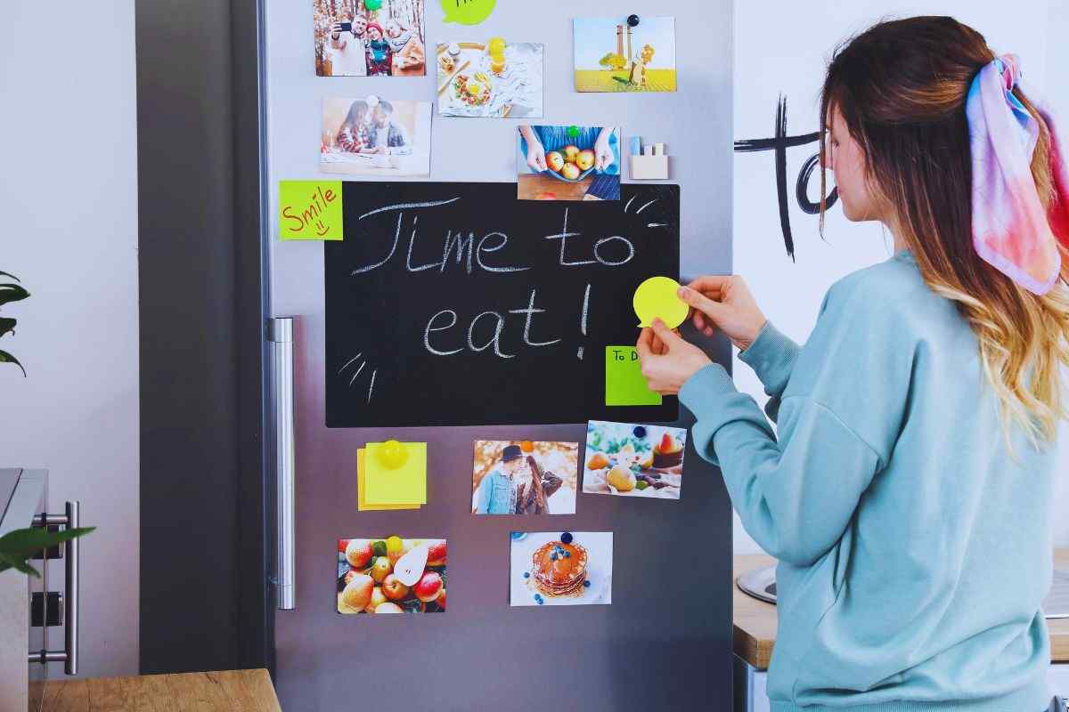 Ragazza che attacca calamite al frigo