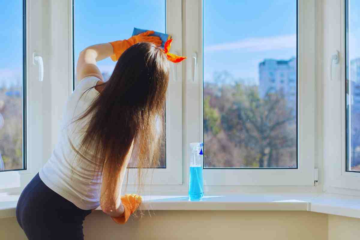 Ragazza che pulisce finestre casa