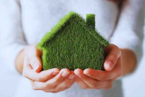 Donna che tiene in mano un modellino di casa fatto con l'erba