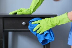 persona pulisce un comodino