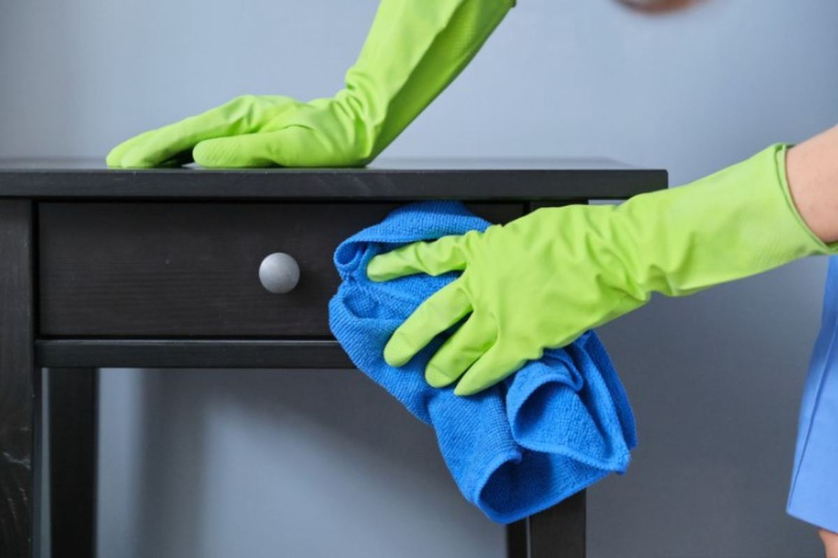 persona pulisce un comodino