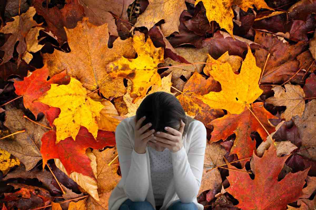 Donna con le mani tra i capelli e foglie autunnali