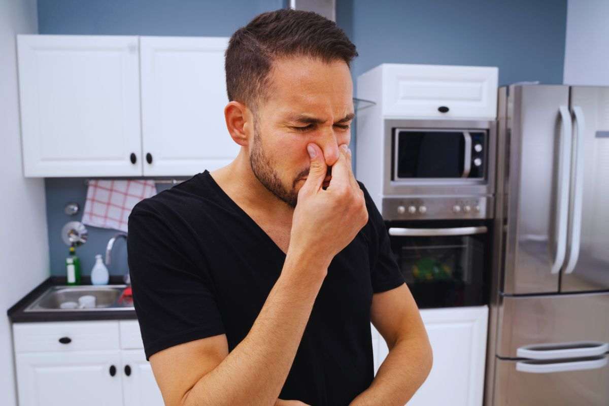 Uomo che si tappa il naso all'interno di una cucina