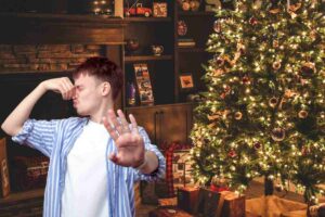 Uomo che si tappa il naso accanto ad albero di Natale