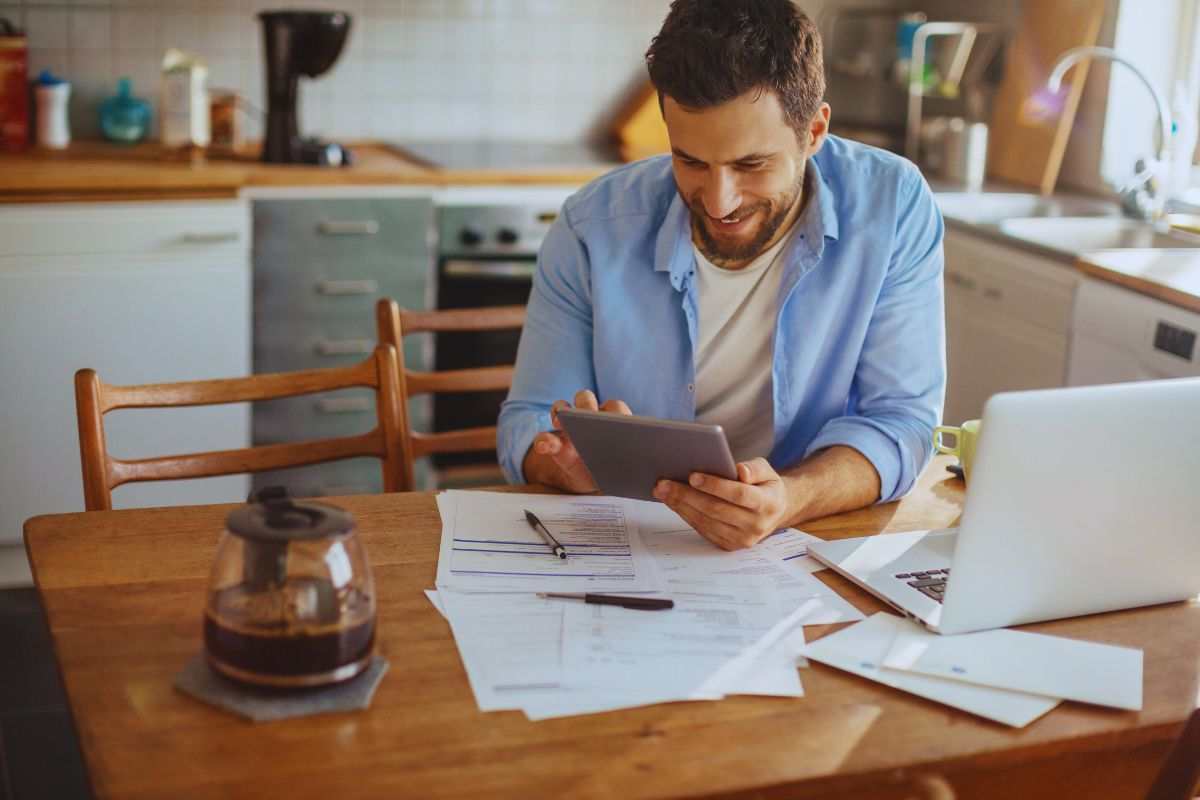 Uomo sorridente che legge messaggio su tablet