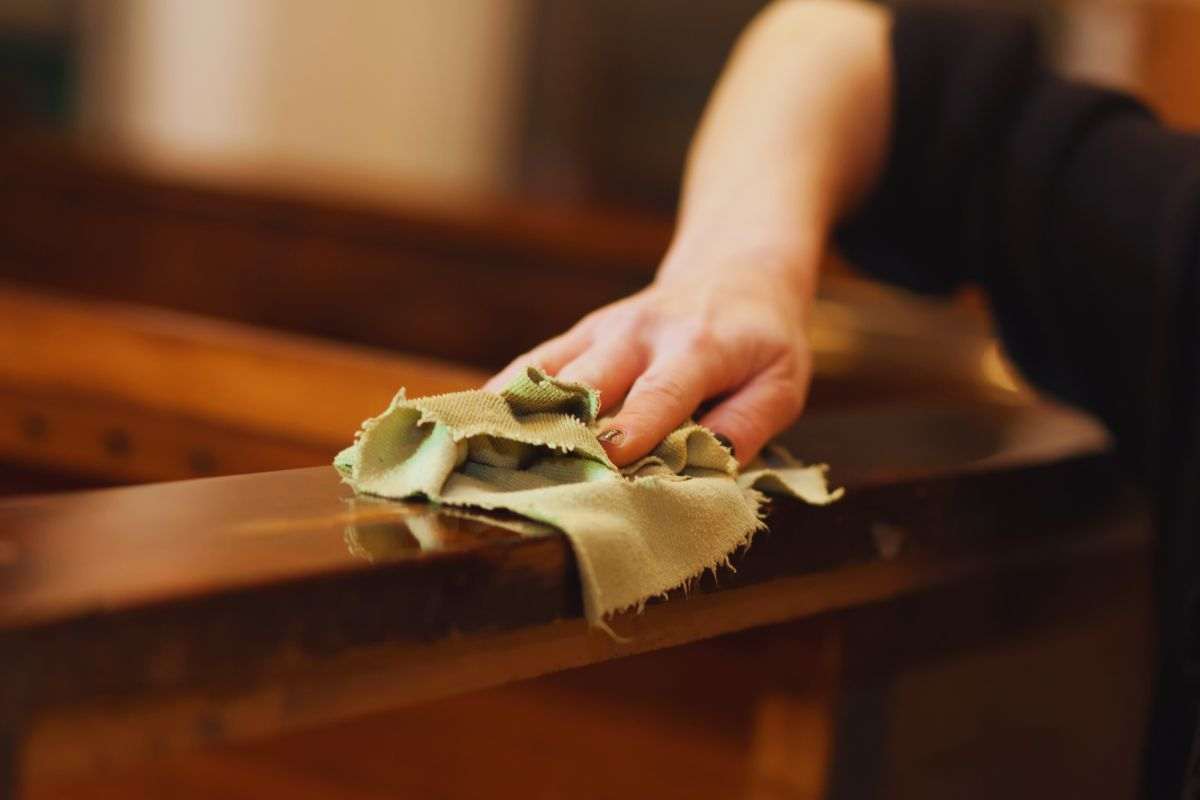 Donna che lucida mobile in legno con un panno