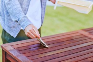 Uomo che passa impregnante su tavolo di legno