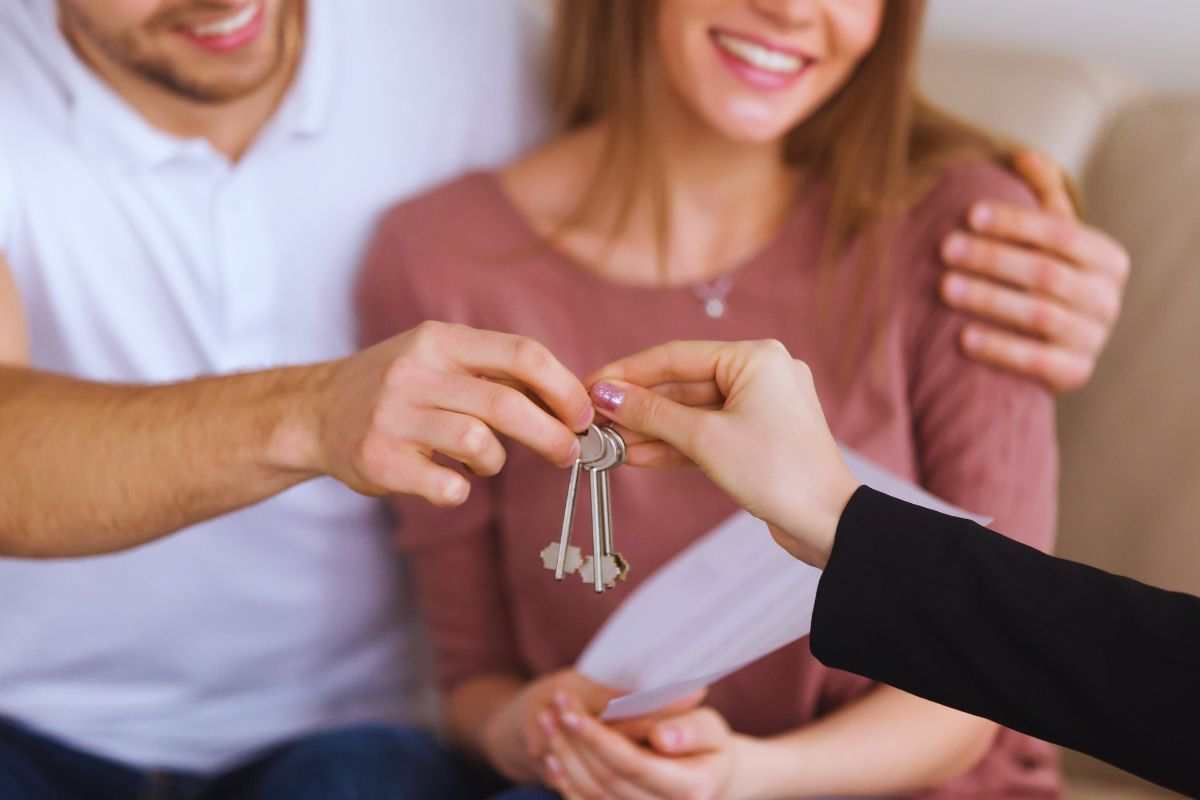 Agente immobiliare che consegna chiavi ad una giovane coppia