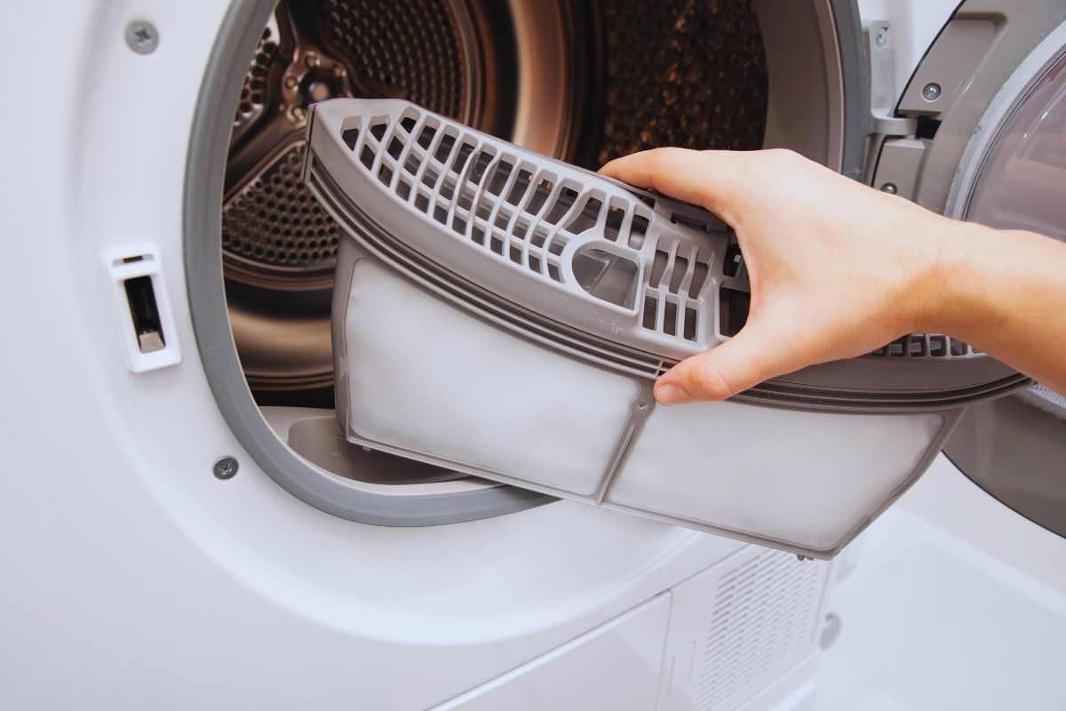 Donna che smonta il filtro dell'asciugatrice