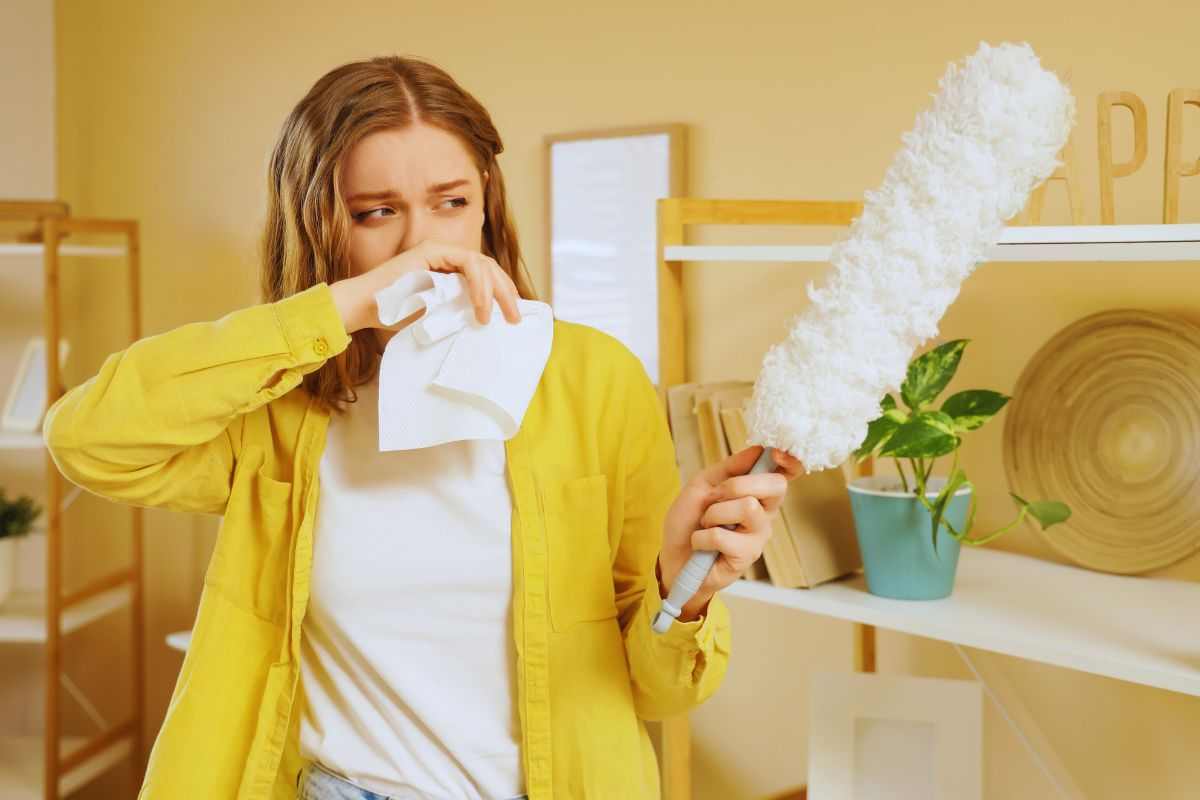 Ragazza che si tappa il naso mentre utilizza uno strumento per rimuovere la polvere