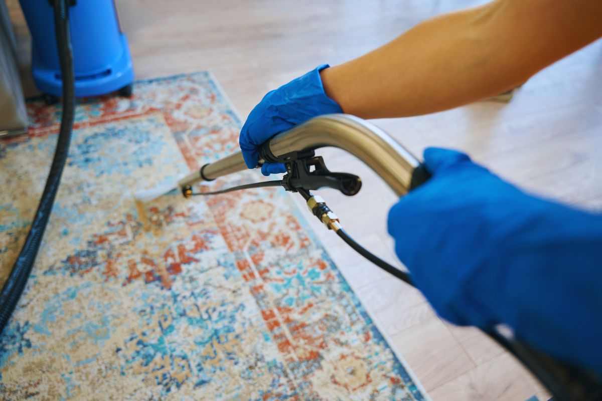 Persona che pulisce un tappeto antico