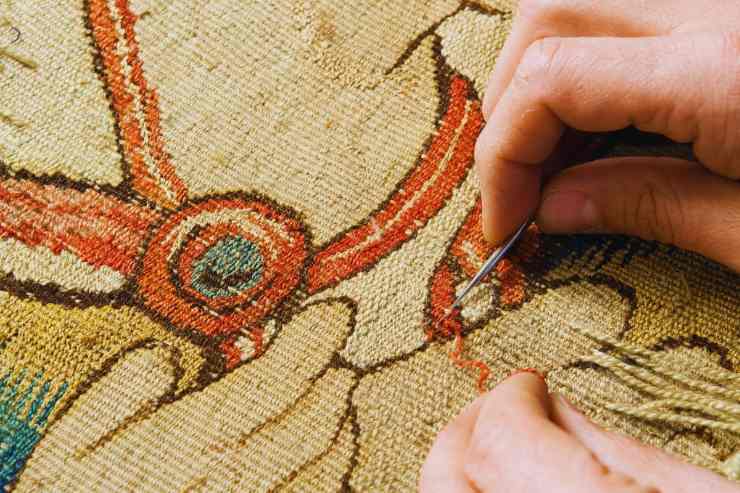 Persona che restaura tappeto antico