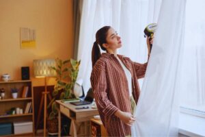 Donna che pulisce tenda con ferro da stiro verticale